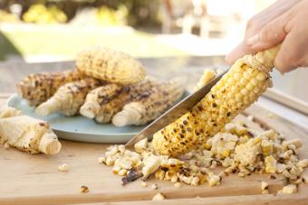 Person cutting grilled corn off the cob