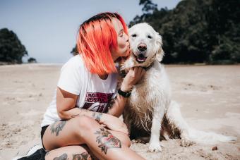 woman and her Golden Retriever dog sitting on the beach