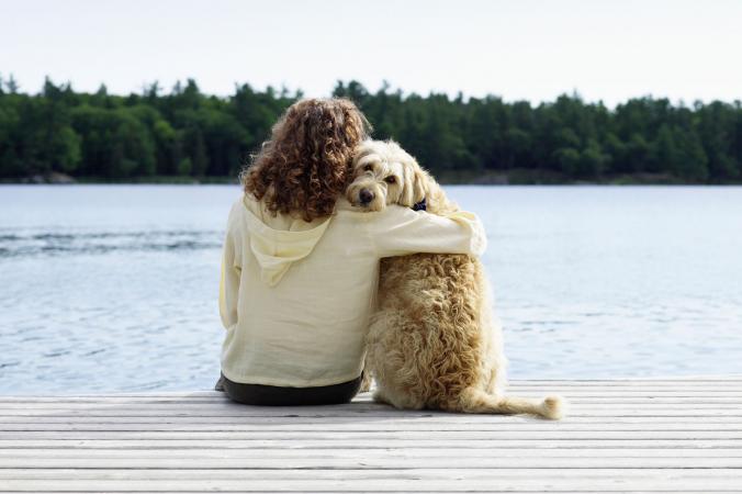 Woman sitting with dog on dock