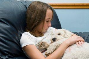 Little girl cuddling her sick dog