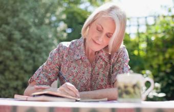 Woman writing in journal at patio table