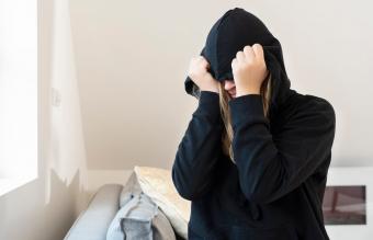 woman covers her face with a hoody