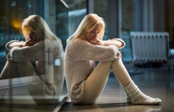 Sad woman sitting on floor at home