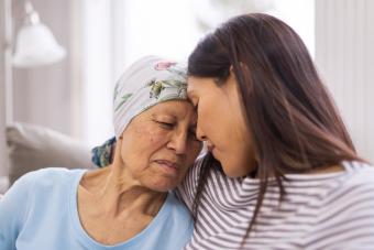 Woman hugging elderly woman with cancer