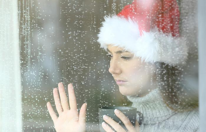 Woman wearing santa hat looking longingly out the window