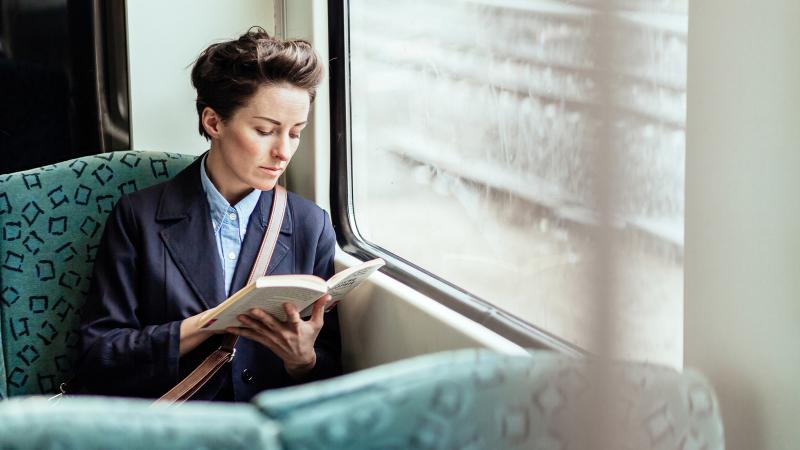 Businesswoman Reading Book In Train