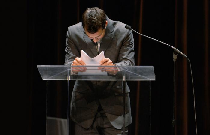 man leaning on podium