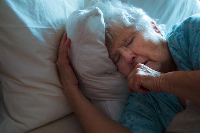 Woman lying in bed coughing