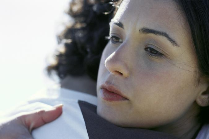 Sad young woman hugging someone