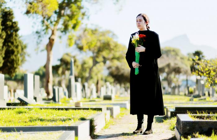 woman carrying flowers on cemetery path