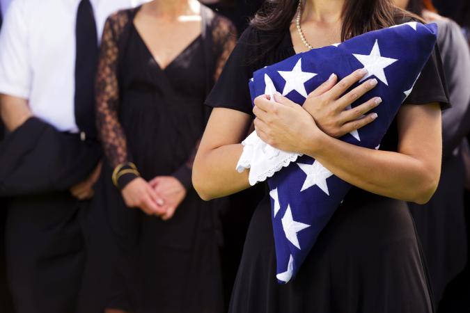 Woman holding a folded American flag at a funeral