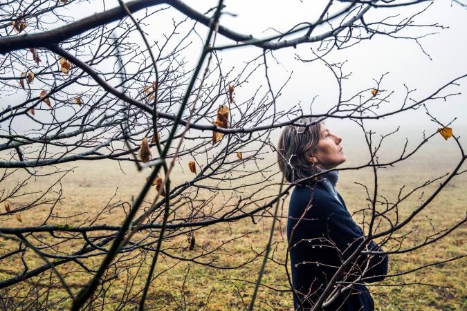 Sad middle age woman walking in winter forest