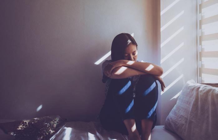 Sad woman sitting on bed at home