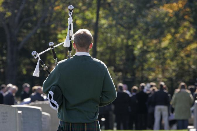 Piper playing bagpipes at funeral