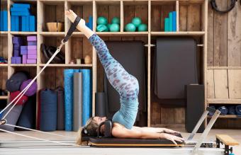 Mujer se estira sobre pilates reformador