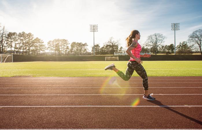Joven atleta femenina corriendo en la pista