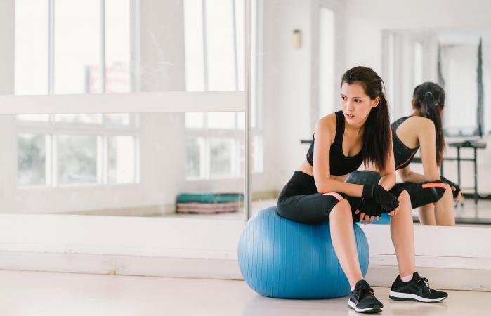 Mujer con pelota de fitness en el gimnasio