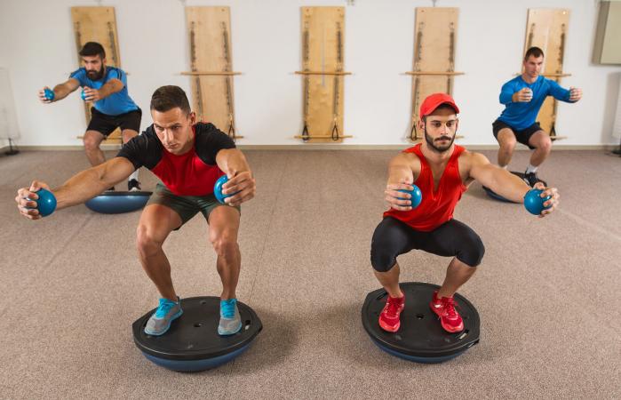 Hombres haciendo sentadillas sobre bosu