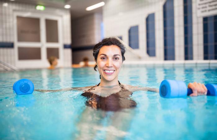 Mujer haciendo ejercicio con mancuernas en la piscina