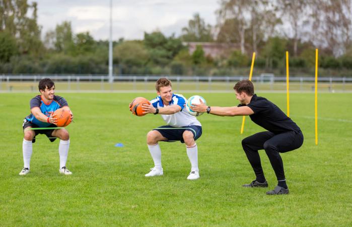 Entrenador haciendo ejercicio con jugadores de fútbol