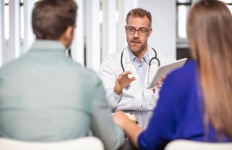 Médico hablando con una pareja en la práctica médica