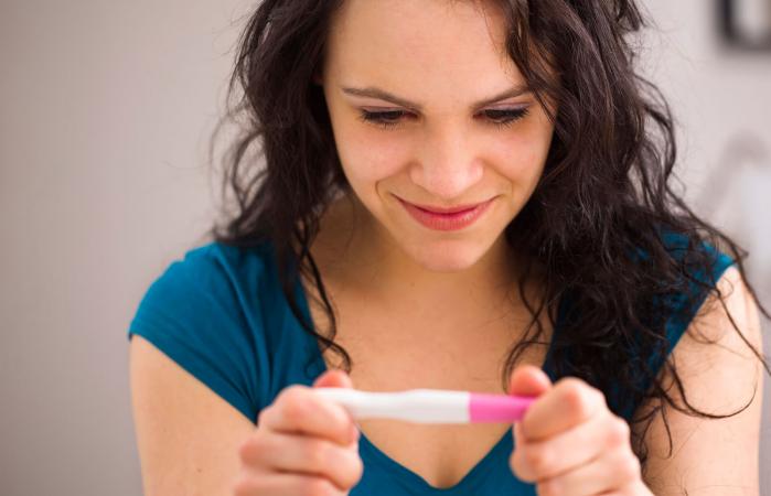 Mujer sonriendo por prueba de embarazo