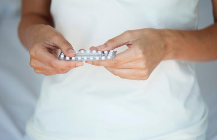 Mujer con pastillas anticonceptivas en la mano