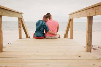 couple sitting on boardwalk against sea