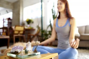 Mujer haciendo yoga en una habitación con incienso y cristales