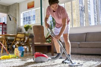 Hombre aspirando y limpiando la casa