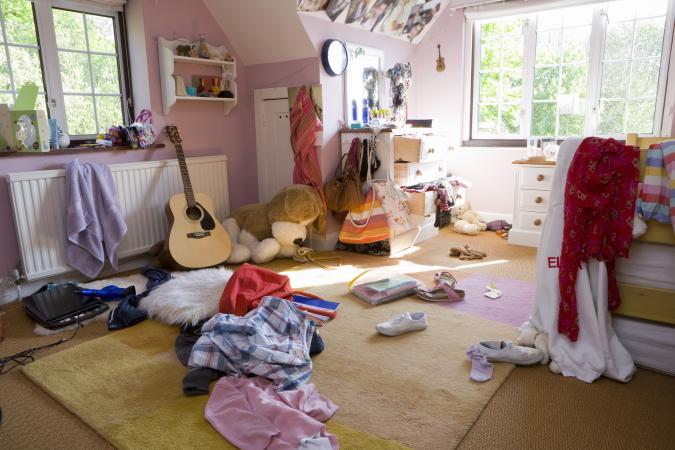 Dormitorio desordenado con ropa en el piso