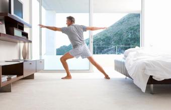 Mature man stretching in yoga stance in bedroom