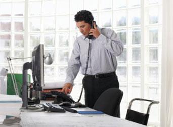 Male using telephone, standing at desk