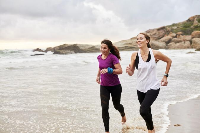 Females running barefoot on beach