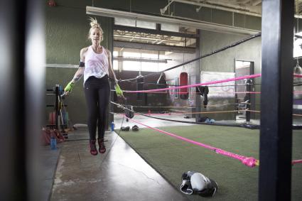 Female boxer jumping rope next to boxing ring