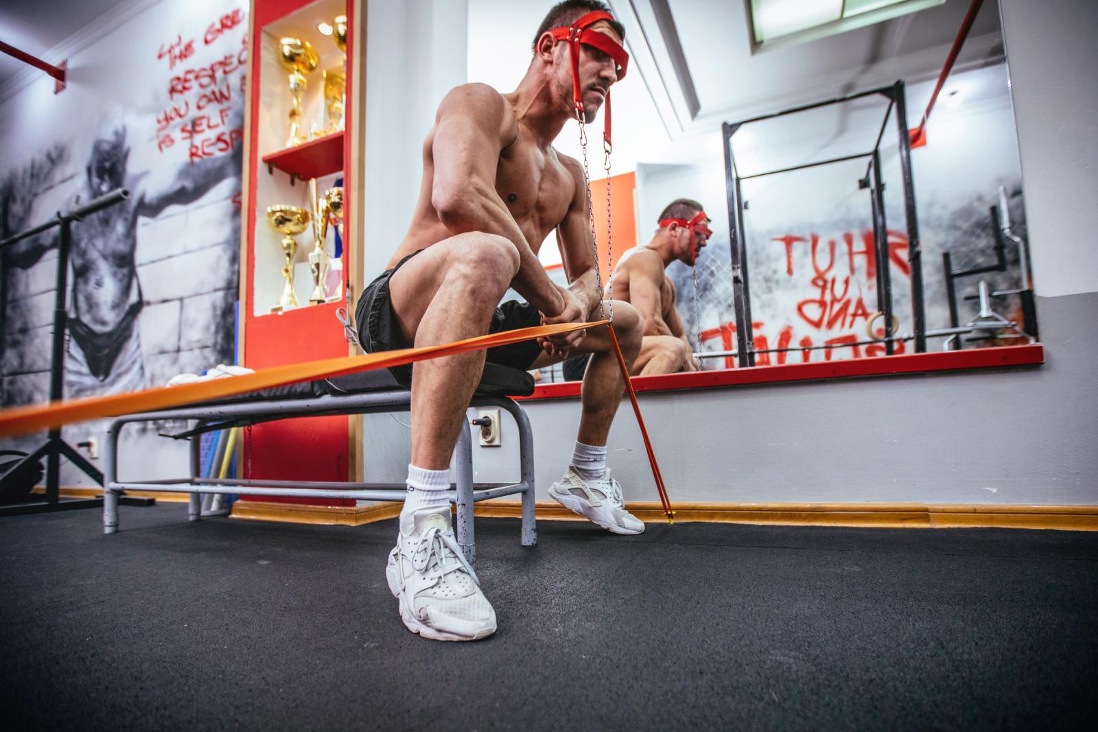 Young muscular man doing neck exercise with weights at gym