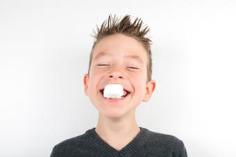 Boy holding marshmallow in his teeth