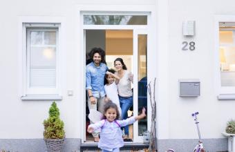 Laughing family waiting at the entrance of their home