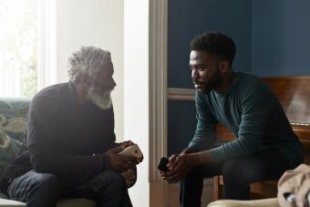 Father and son talking while sitting in living room 