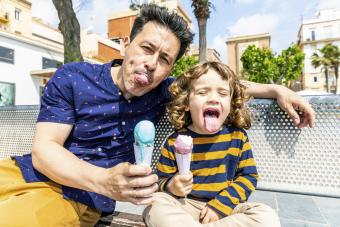 Happy father and son sitting on bench enjoying an ice cream