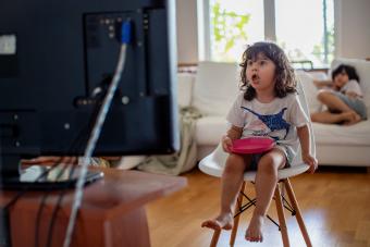 Three year old toddler eating in front of a television