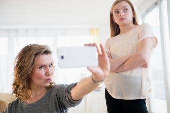 girl embarrassed of mother taking selfies with cell phone