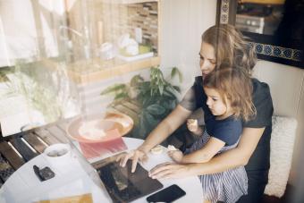 Mother using laptop while daughter sitting on lap