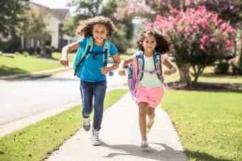 Young girls running outside wearing backpacks