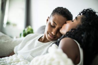 couple at home snuggling under blanket 