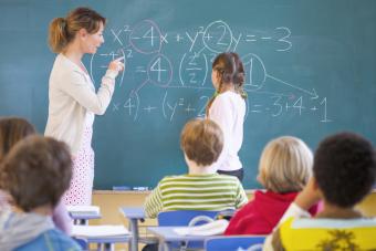 Primary school teacher explaining equation on classroom blackboard