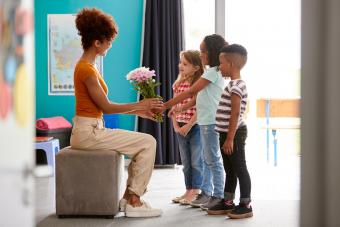 Group Of Elementary School Pupils Giving Female Teacher Thank You Gift Of Flowers