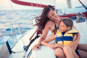 Mother and daughter sitting in cockpit while sailing over nice sea after sunset