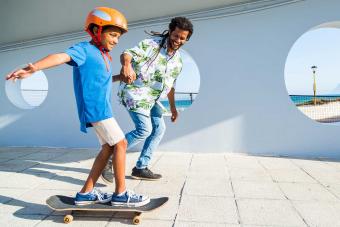 father teaching son how to skateboard