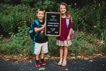 brother and sister holding sign first day of school